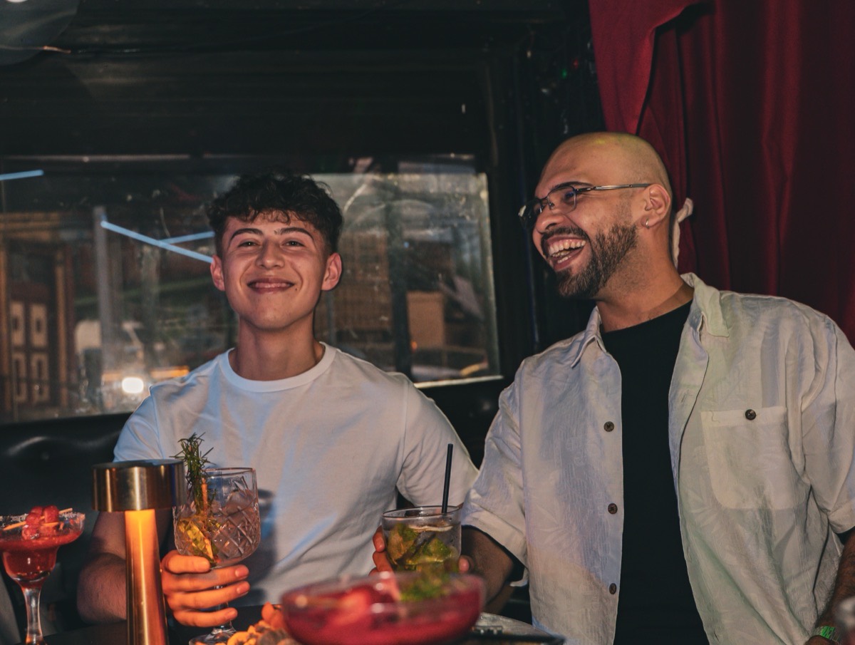 Dos amigos celebrando con cocteles en una mesa de La Santa